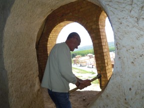 Jose Ruiz Ruiz hackt mit einem Hammer eine Tür in eine Höhlenwohnung.