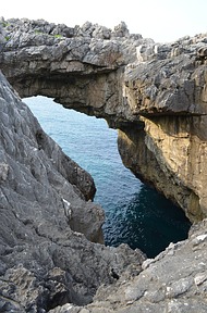 Meer und Kalkstein = bizarre Steilküste. An dieser Stelle nahe dem Playa Ballota findet sich ein weiterer Mini-Inlandsstrand und eine Höhle, durch die man zum Ufer gelangt. Foto: Gabriela Heidegger